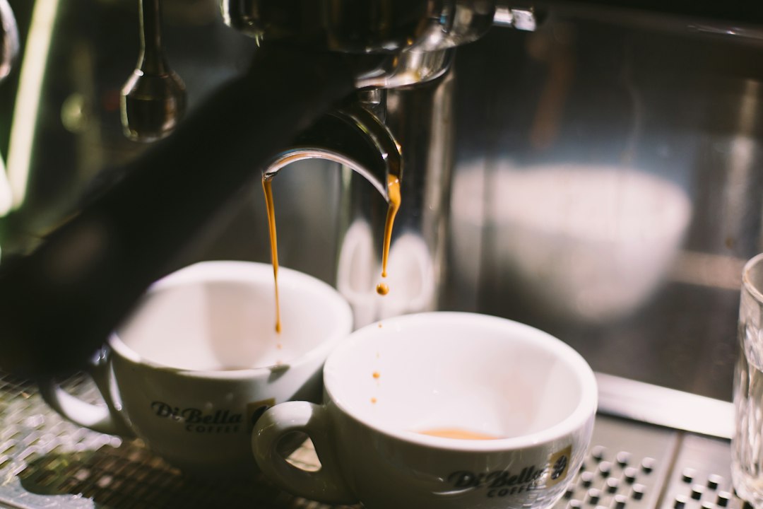 Two ceramic mugs on a coffee maker illustrating Breville Barista Express vs Barista Pro.