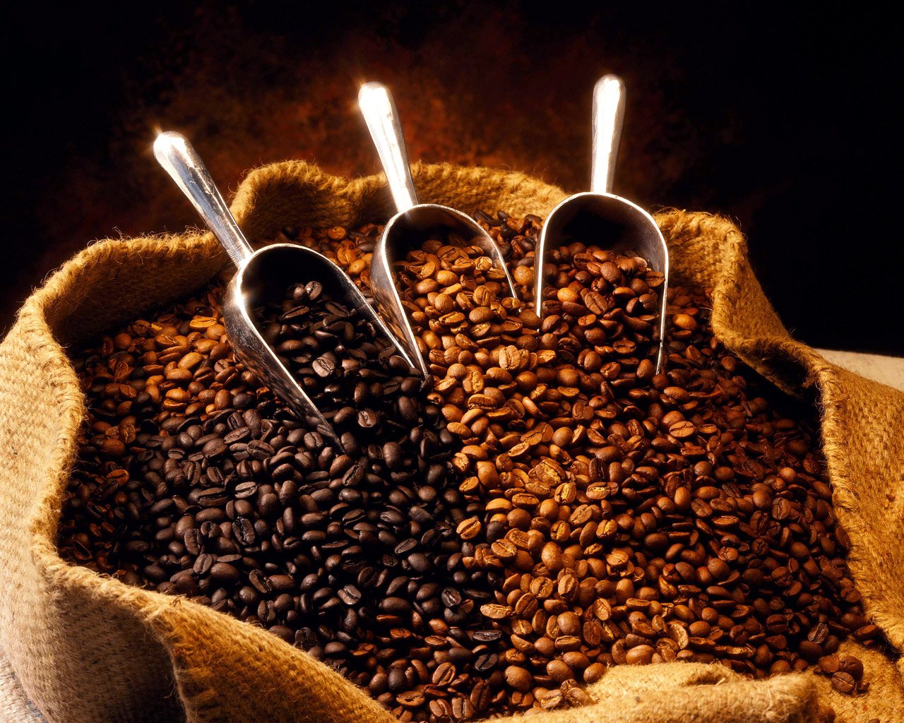 An espresso machine pulling a shot with rich crema beside a latte, roasted nuts, caramels, and chocolate on a wooden counter, illustrating a Brazilian natural coffee for espresso.