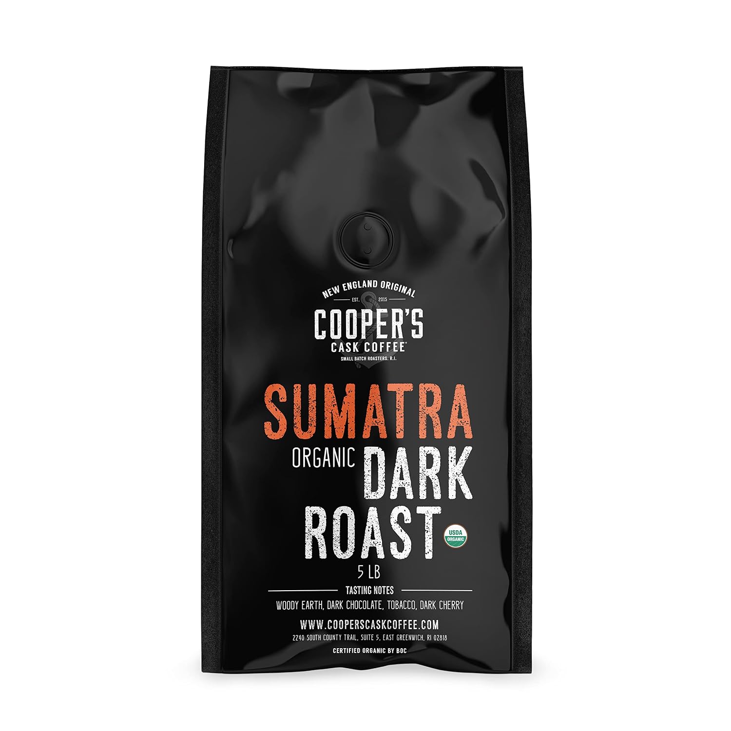 A steel French press and a stoneware mug of black coffee on cedar with dark-roast beans, dark chocolate, molasses, and dark cherries beside tropical leaves, illustrating a smooth dark roast to drink black.
